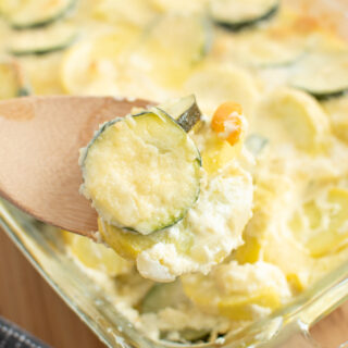 Baked zucchini and squash on a wooden spoon lifted from casserole baking dish.