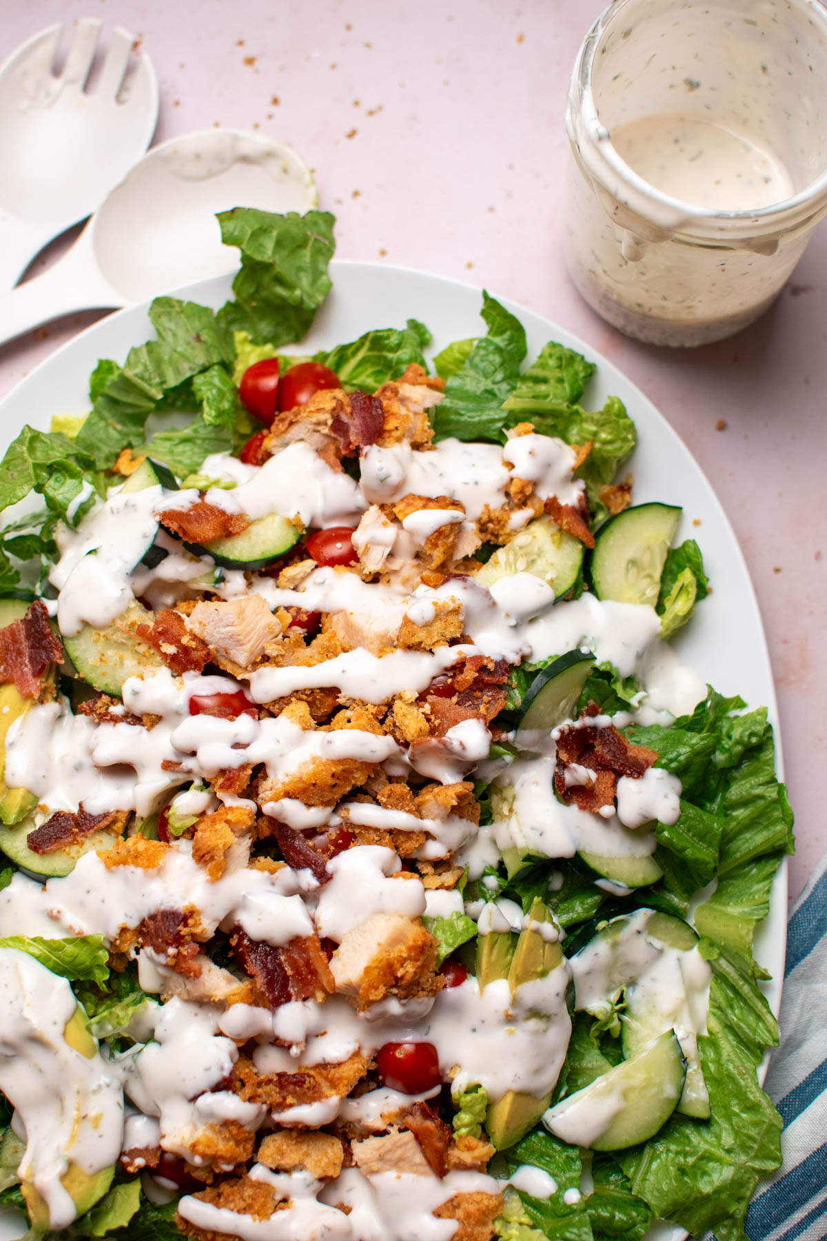 BLT salad with crispy chicken and ranch dressing drizzled over the top on white platter.