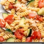 Pinterest graphic with text and photo of cold rotini pasta salad with tomatoes.