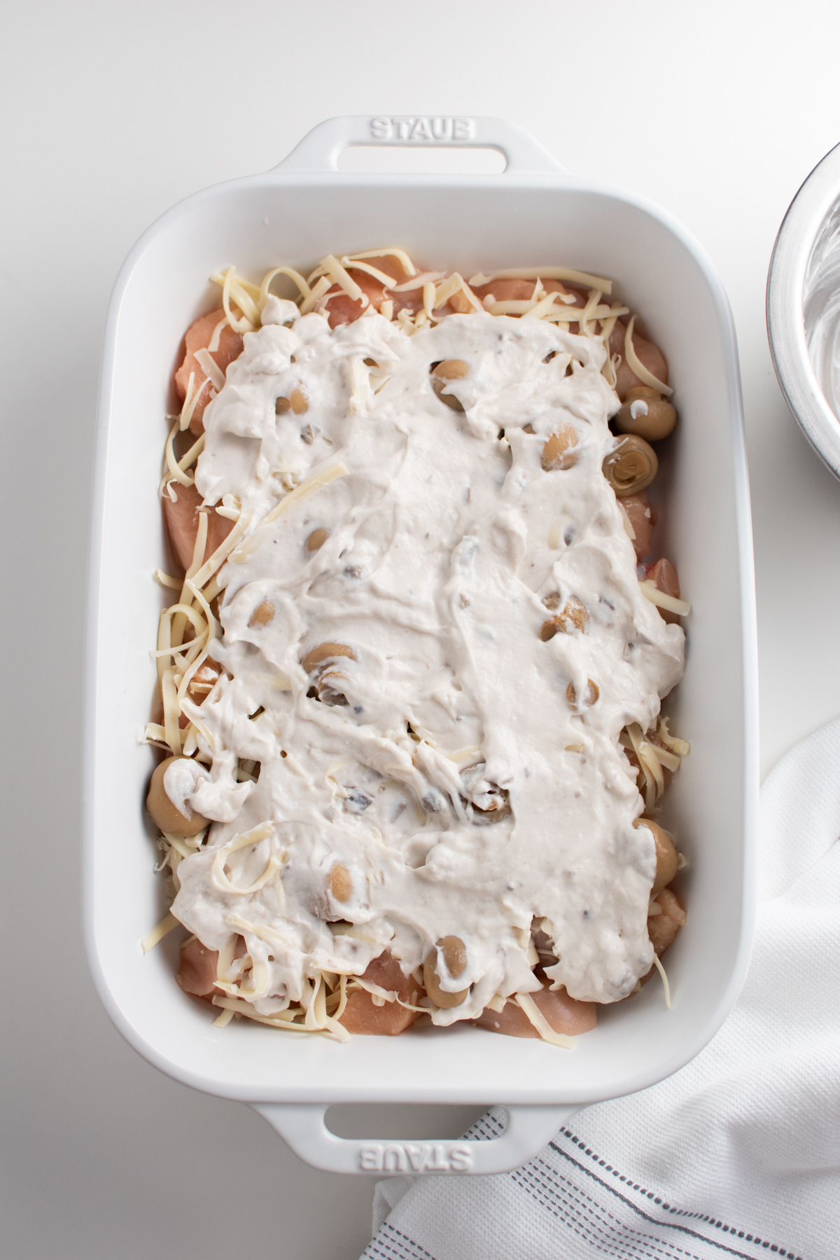 Creamy swiss chicken bake in white dish before being put in the oven.