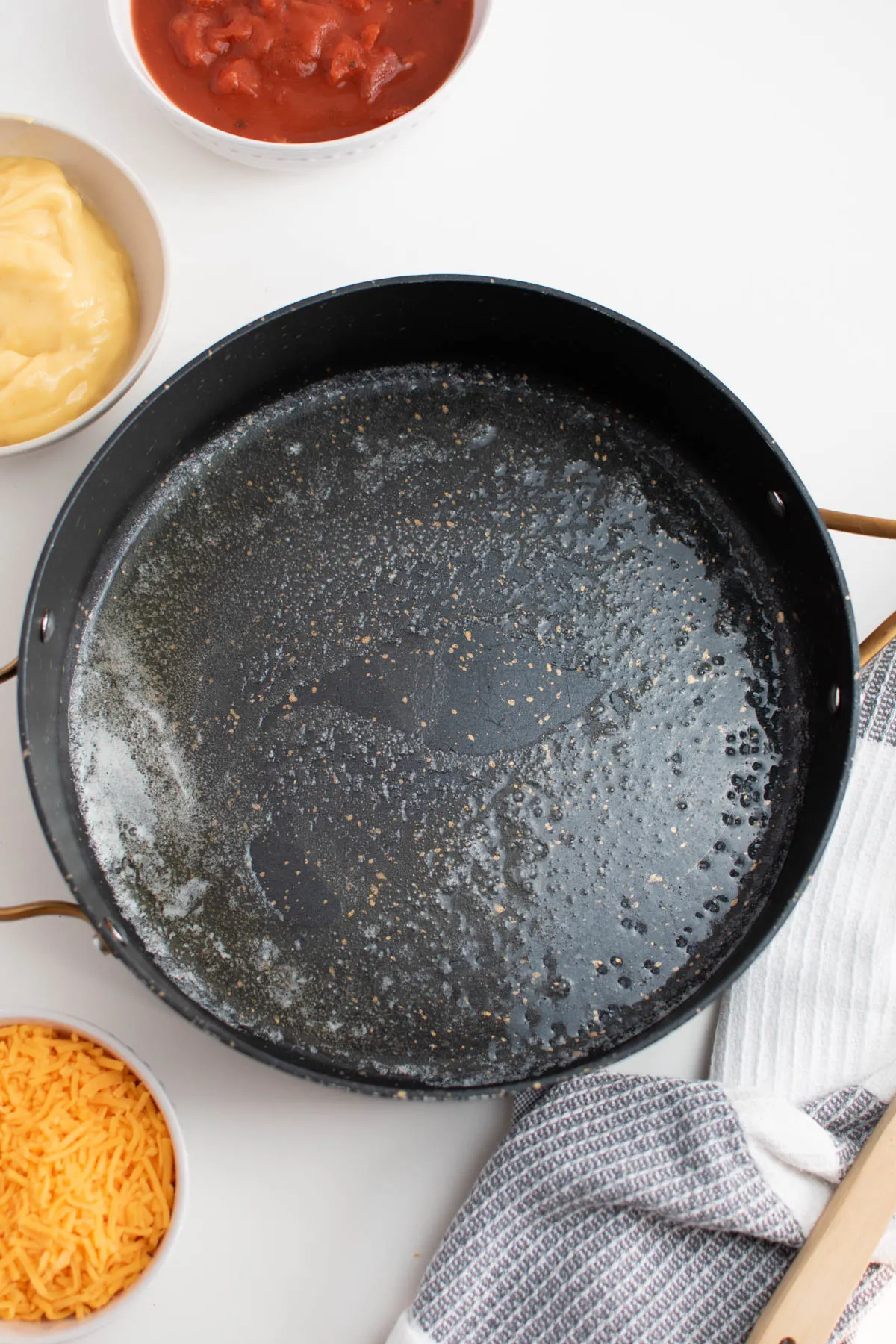 Melted butter in large skillet surrounded by bowls of various ingredients.