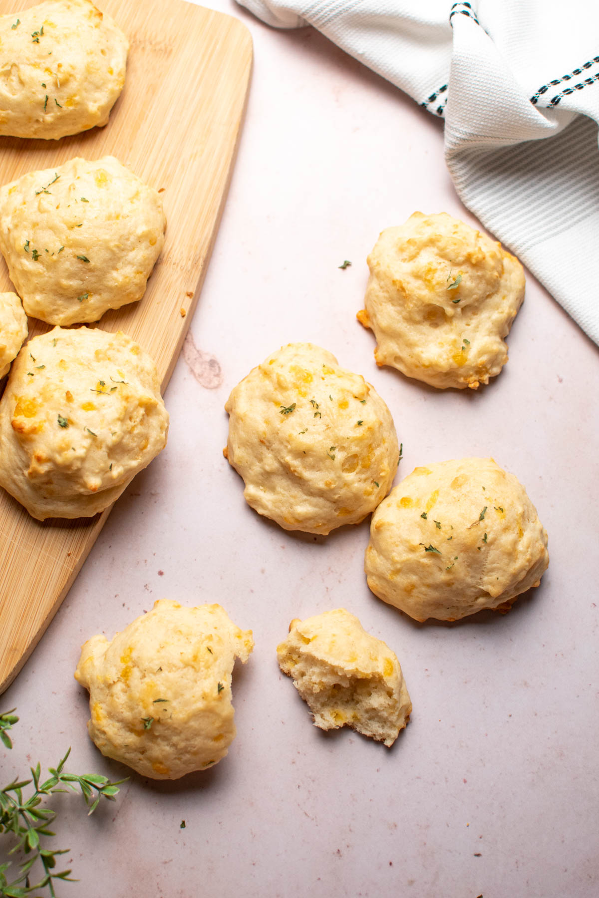 Several cheesy biscuits without butter on counter and wood cutting board.