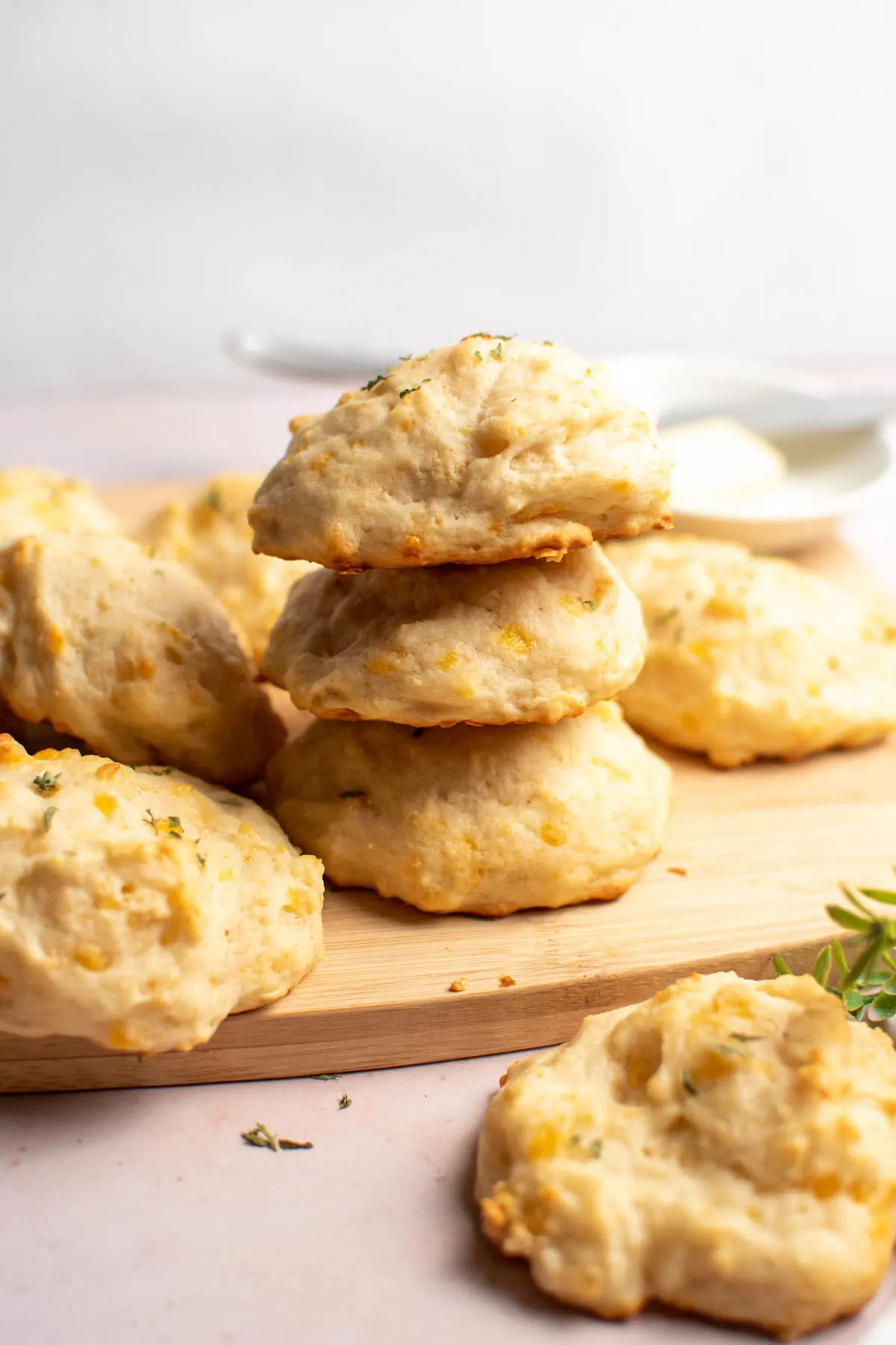Stack of three parmesan cheese biscuits on wood cutting board with more biscuits surrounding.