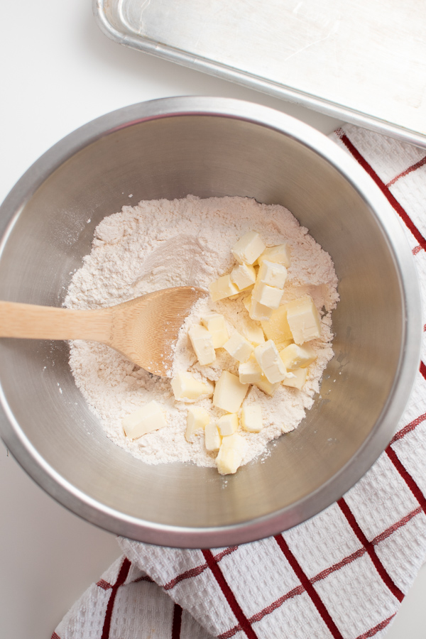 Thumbprint ingredients in a mixing bowl including flour and diced butter cubes.
