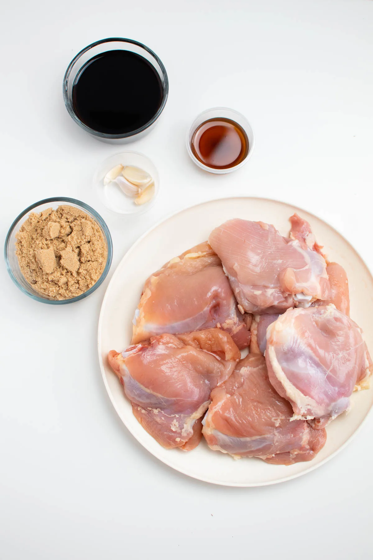 Asian chicken thigh ingredients on table including chicken thighs, brown sugar, and soy sauce.