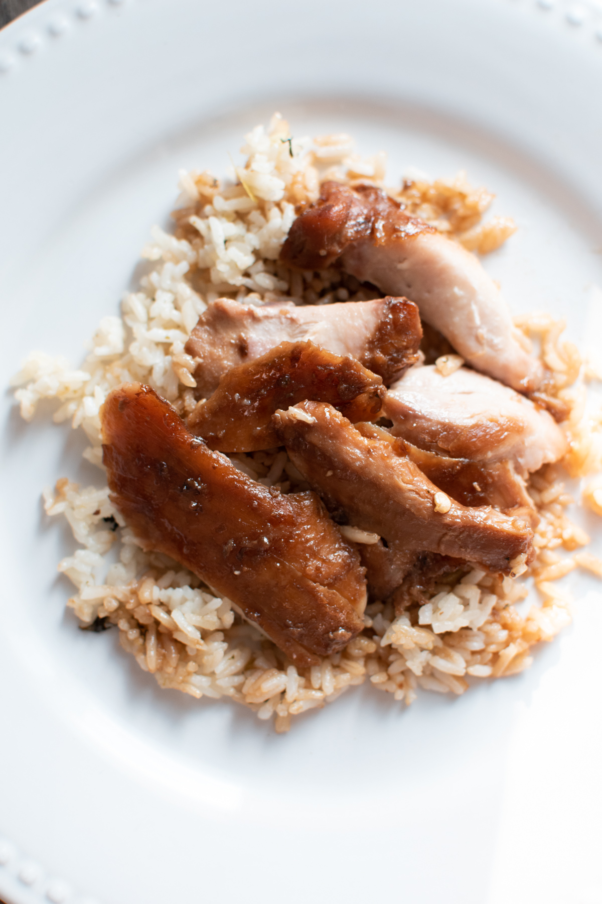 Asian style chicken thighs served over rice and a large white dinner plate.