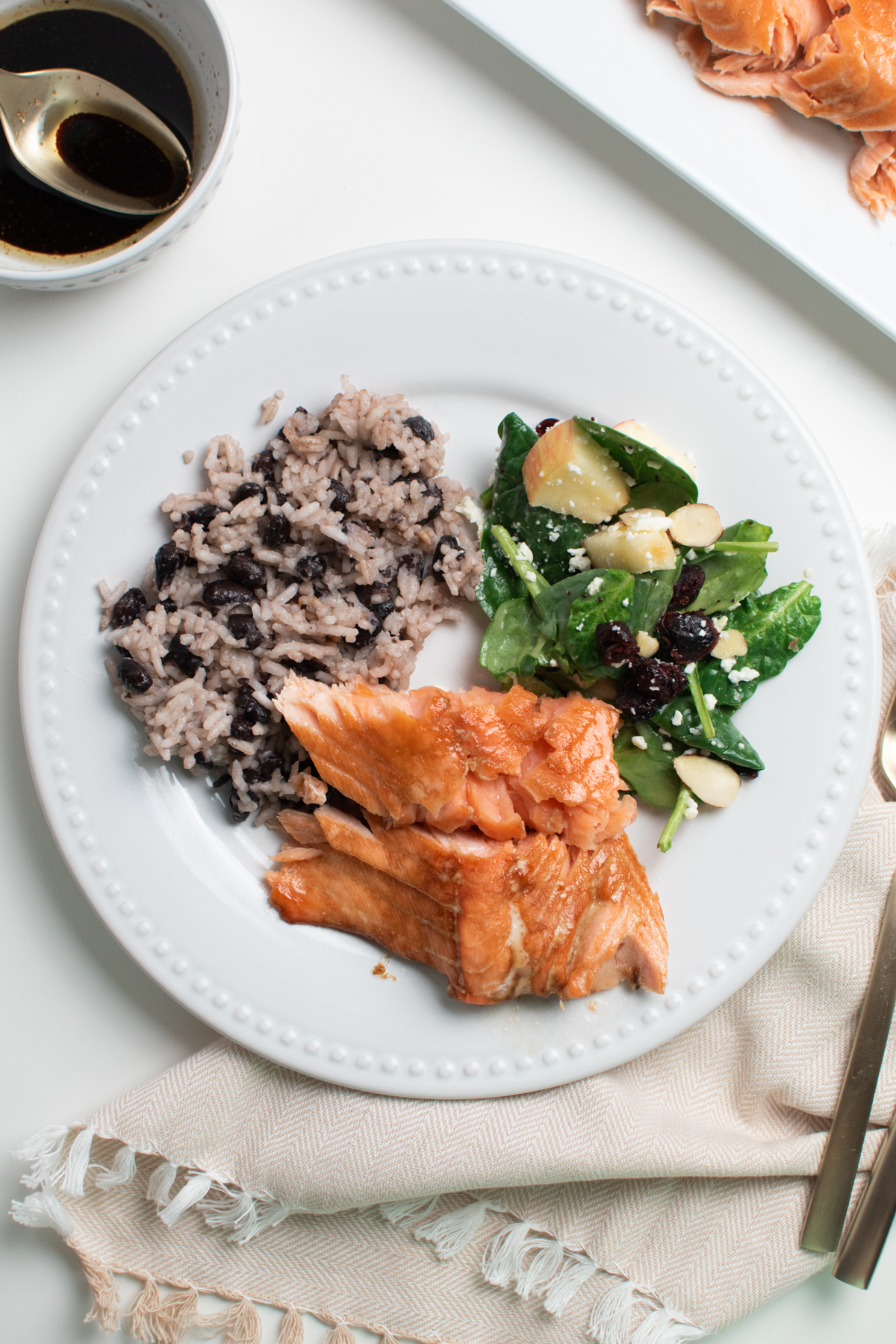 Brown sugar baked salmon on white dinner plate with rice and beans.