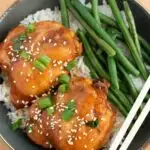 Pinterest graphic with text and bowl of crock pot Asian chicken thighs over white rice with green beans.
