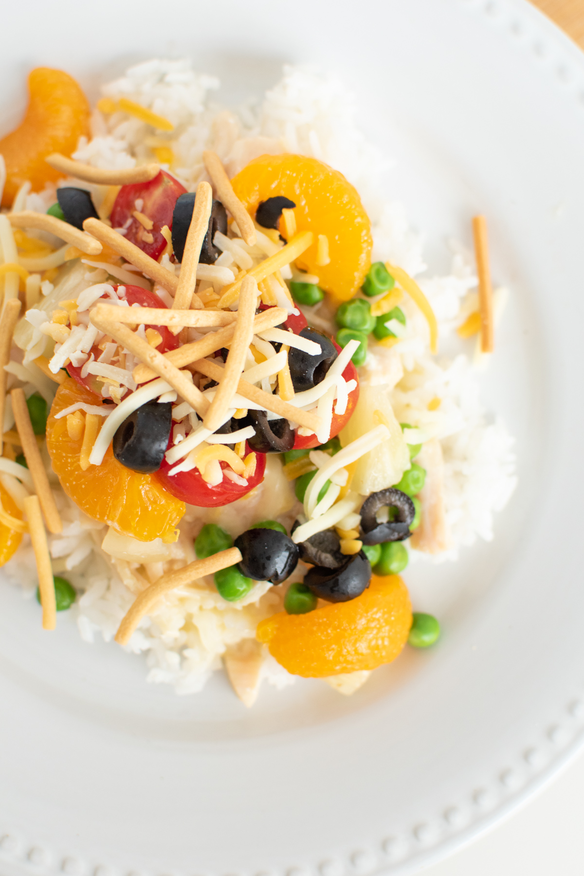 Hawaiian haystacks with sauce over rice with mandarin oranges, olives, peas and tomatoes.