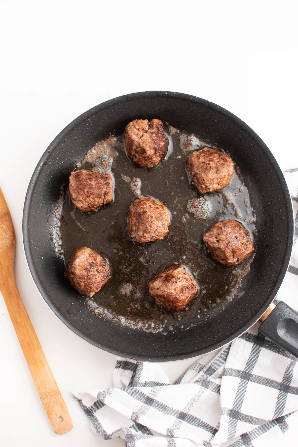Authentic homemade meatballs for spaghetti in a frying pan on white table.