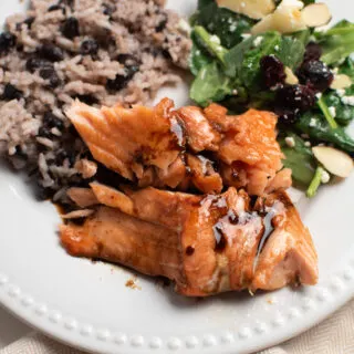 Salmon recipe with brown sugar on white plate with salad and coconut black bean rice.
