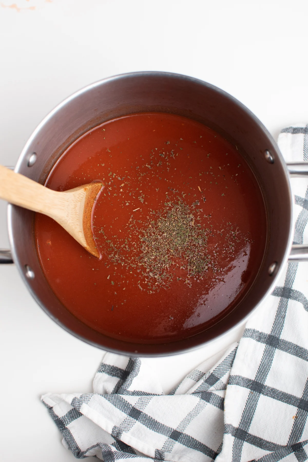 Spaghetti sauce with spices on top in a pot on white table.
