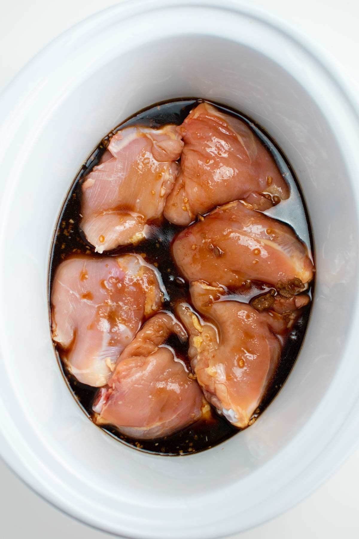 Six uncooked chicken thighs and marinade in Crock Pot.