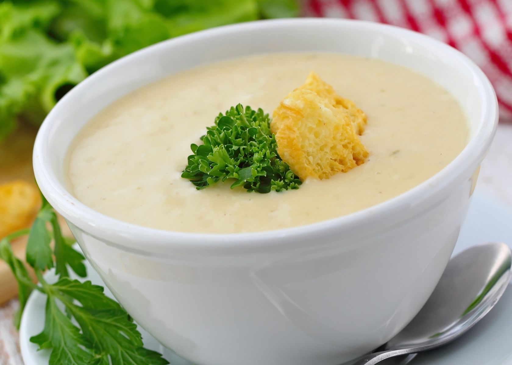 Cream of chicken soup in white bowl with green garnish and crouton.