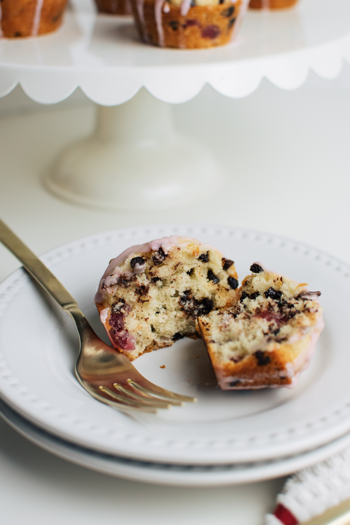 Easy chocolate chip muffins with cherries on stack of white dinner plates.