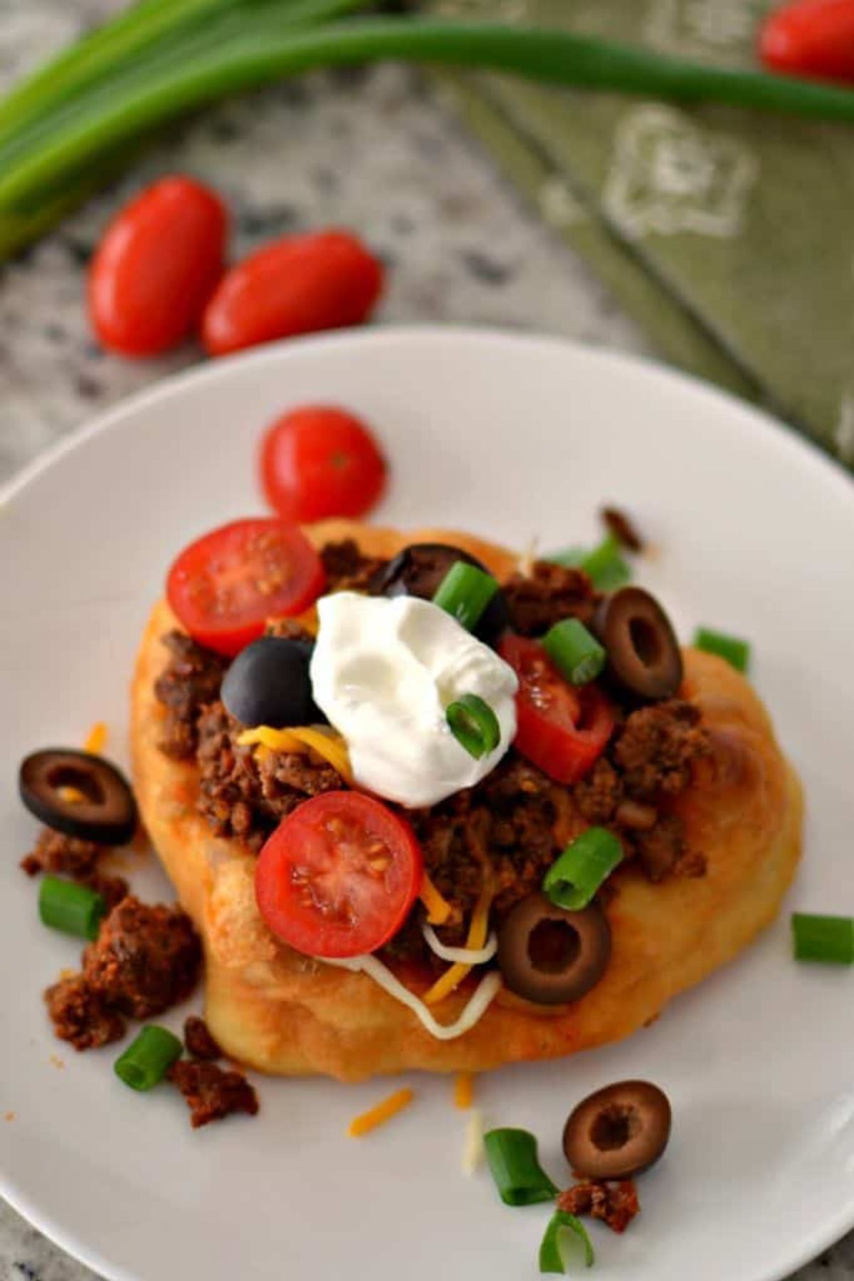 Fry bread made into a Navajo taco with sour cream and green onion.
