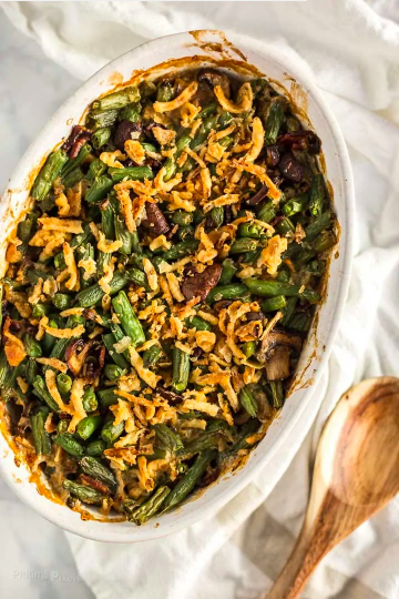 String bean casserole with candied bacon and French fried onions in casserole dish.