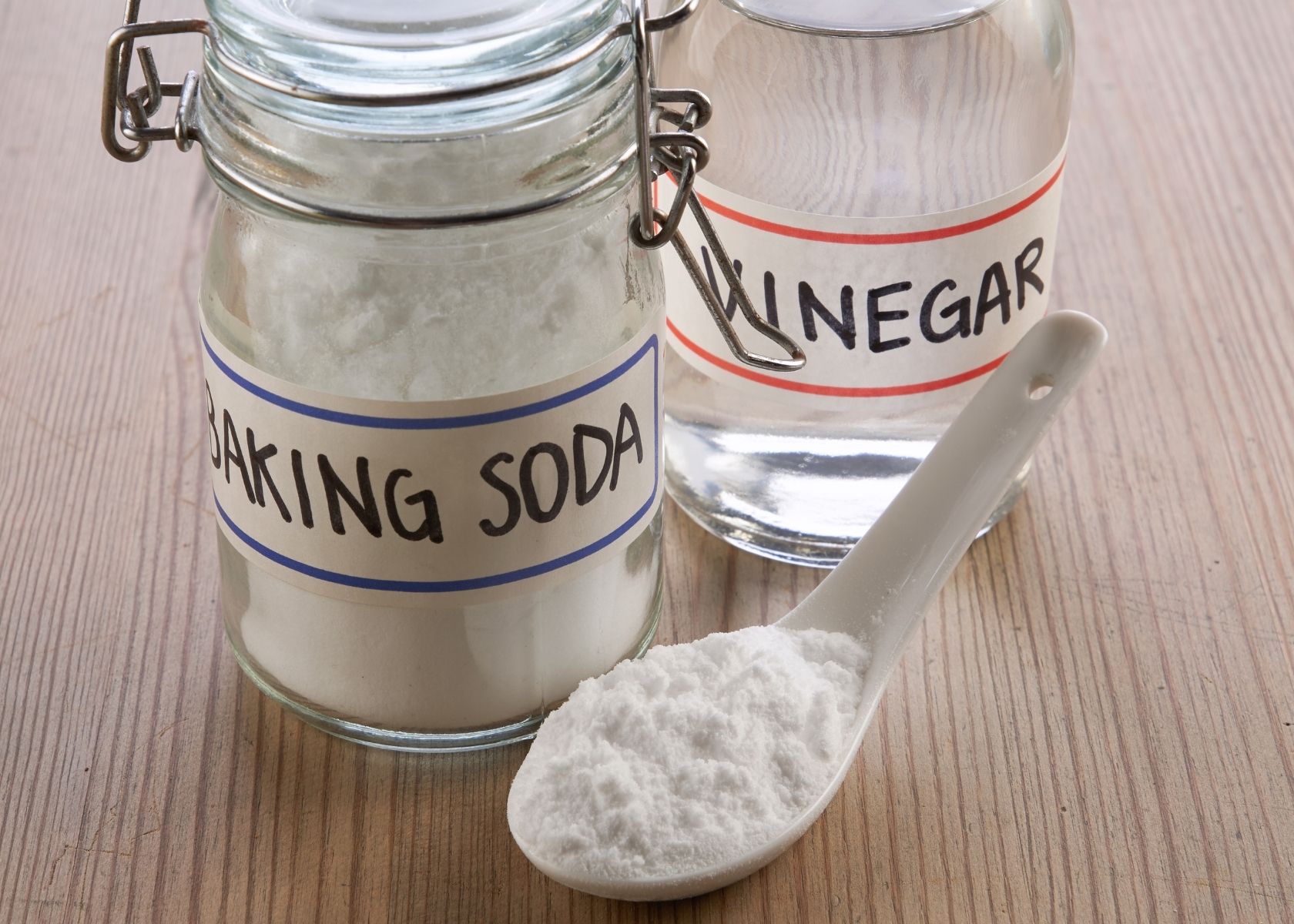 Baking soda and vinegar in glass mason jars next to plastic ladle.