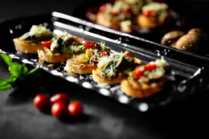 Crispy bruschetta appetizer bites with tomato and cheese on pieces of bread.