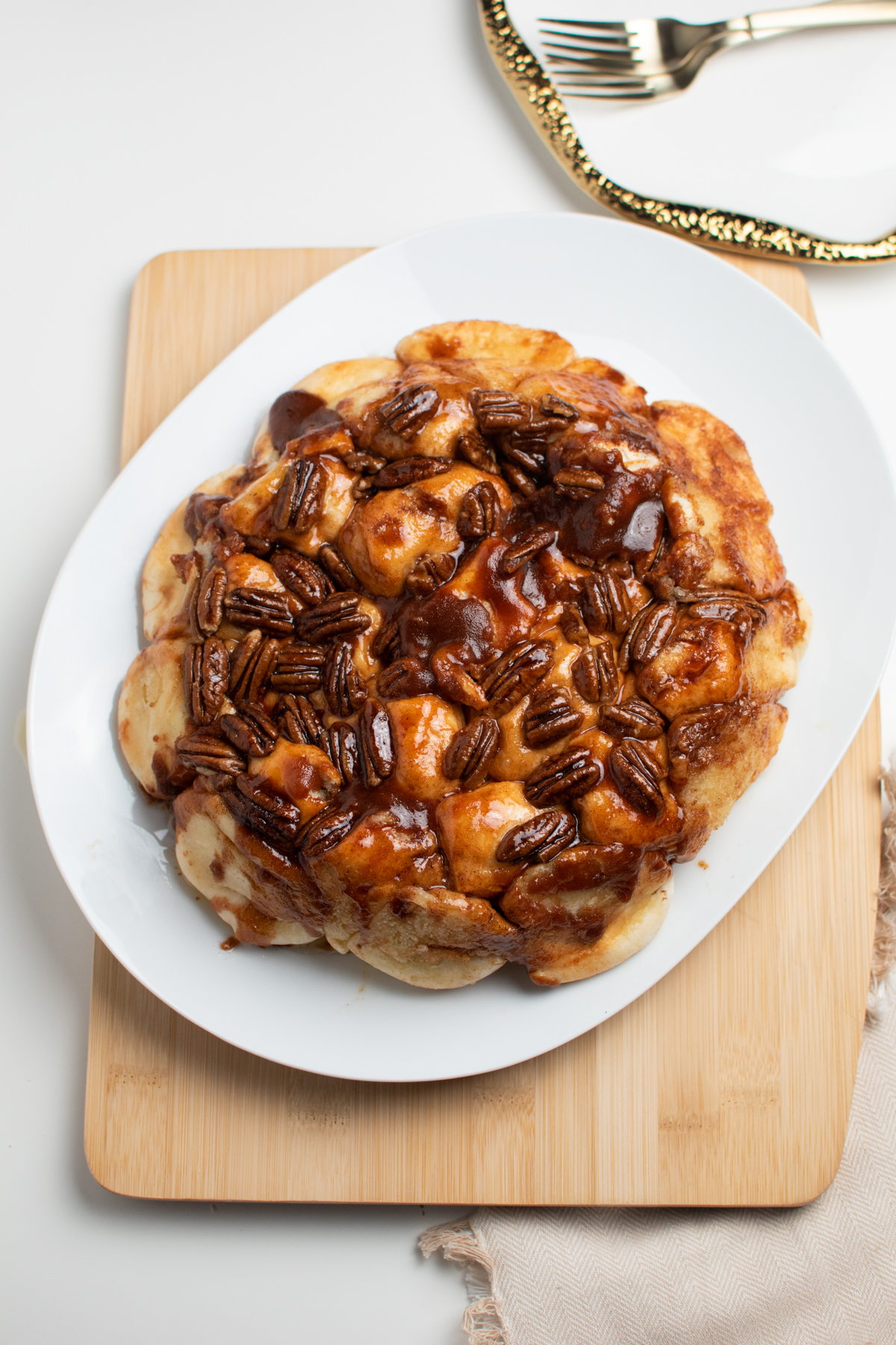 Overnight sticky buns on large white serving platter topped with sugary pecans.
