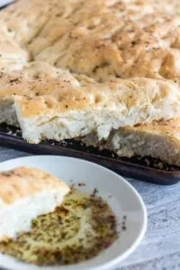 Pieces of sea salt and pepper focaccia bread on metal baking sheet.