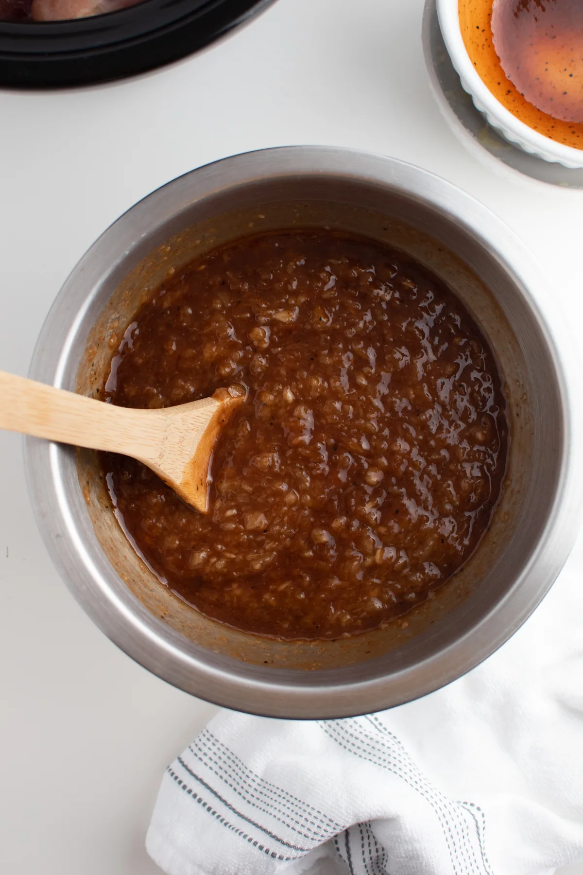 BBQ pineapple sauce in large metal mixing bowl with wooden spoon inside.