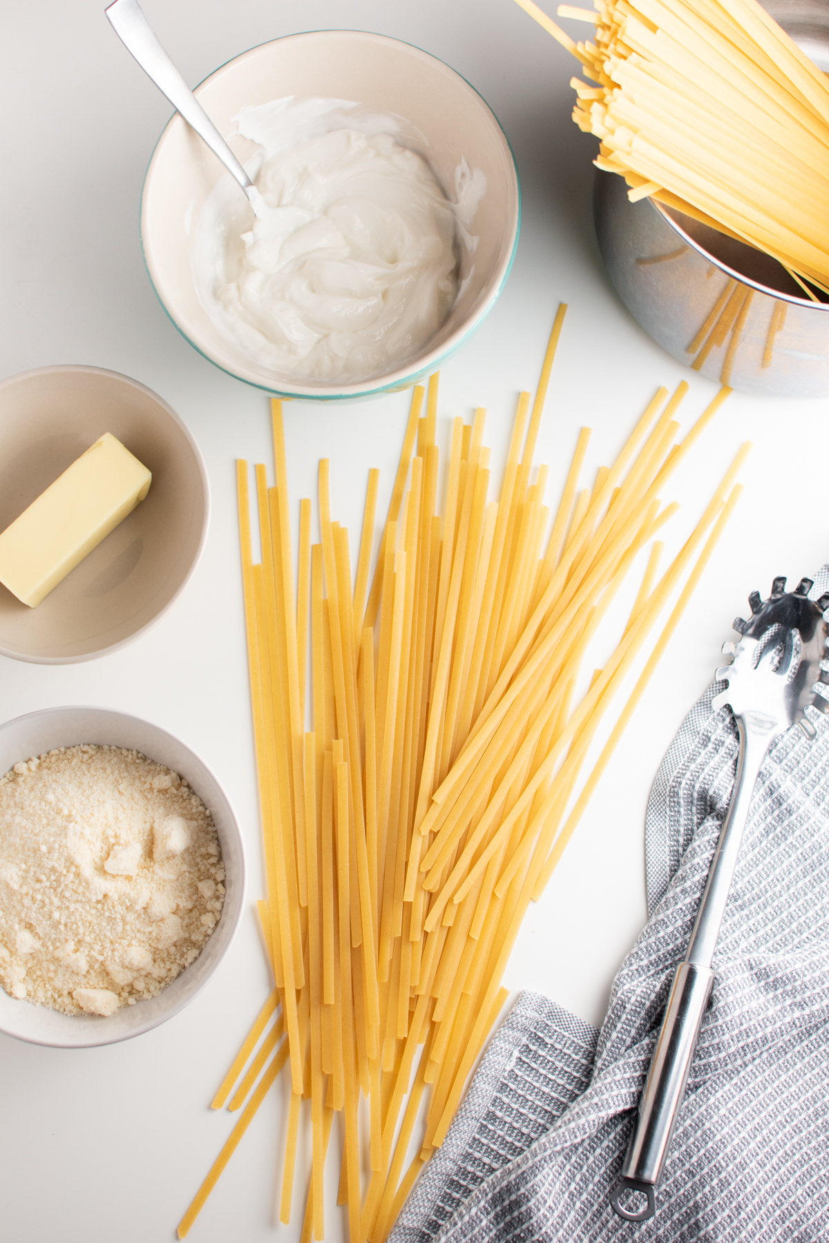 Healthy fettuccine alfredo ingredients including pasta, parmesan, butter and Greek yogurt.
