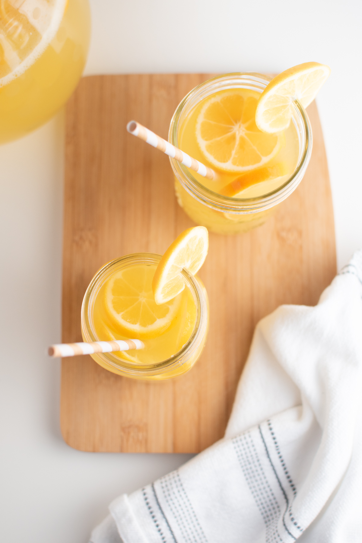 Lemonade with Meyer lemons in glass mason jar cups on cutting board.