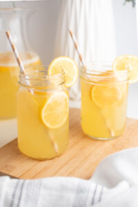 Two glass mason jars of Meyer lemonade with white and gold striped straws.