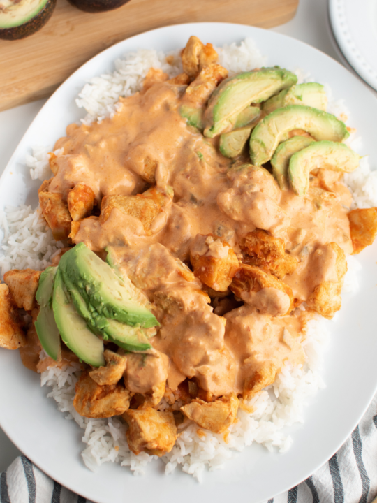 Platter of picante chicken and avocados over rice.