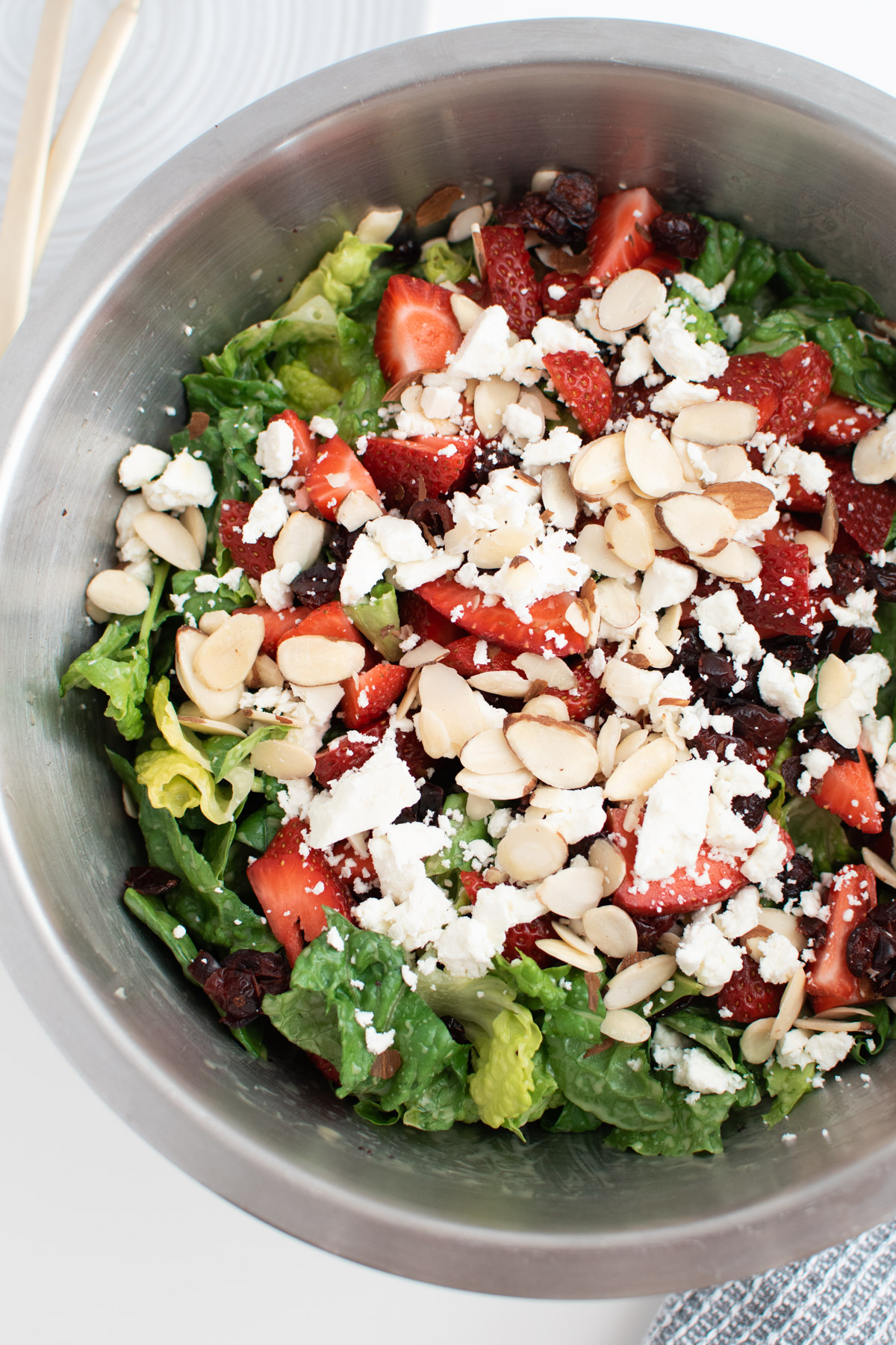 Large mixing bowl filled with spinach strawberry almond salad with feta cheese.