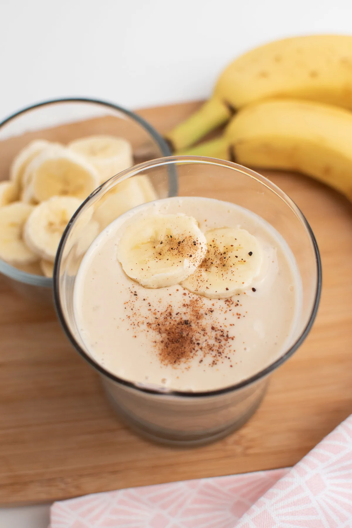 Close up of banana and ice smoothie with nutmeg and banana slices in glass.