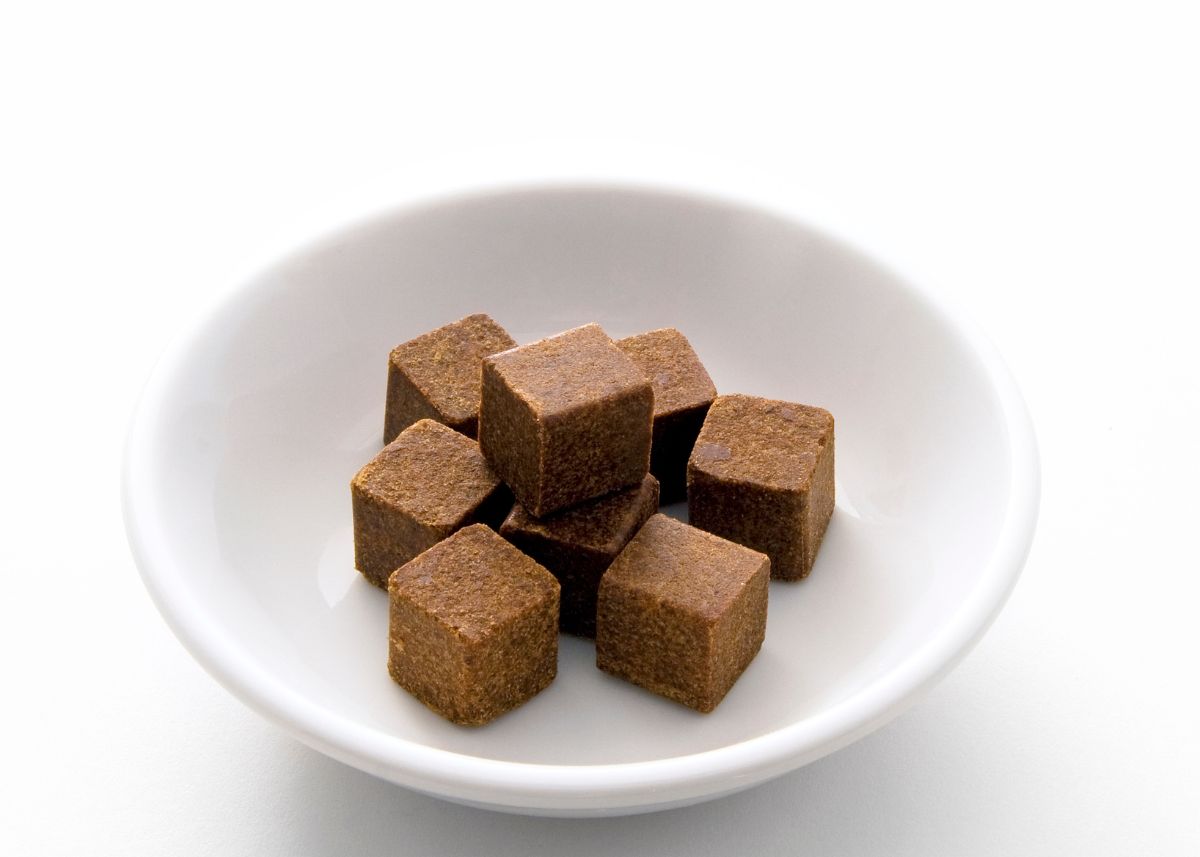 Several beef bouillon cubes stacked in white bowl on white table.