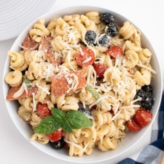 Pasta salad to go with pizza in a white bowl.