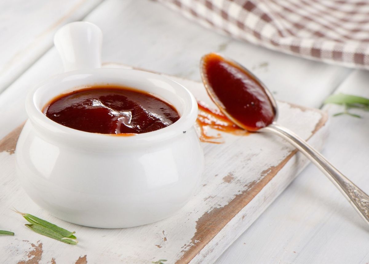 Steak sauce in small white serving bowl with handle next to spoon.