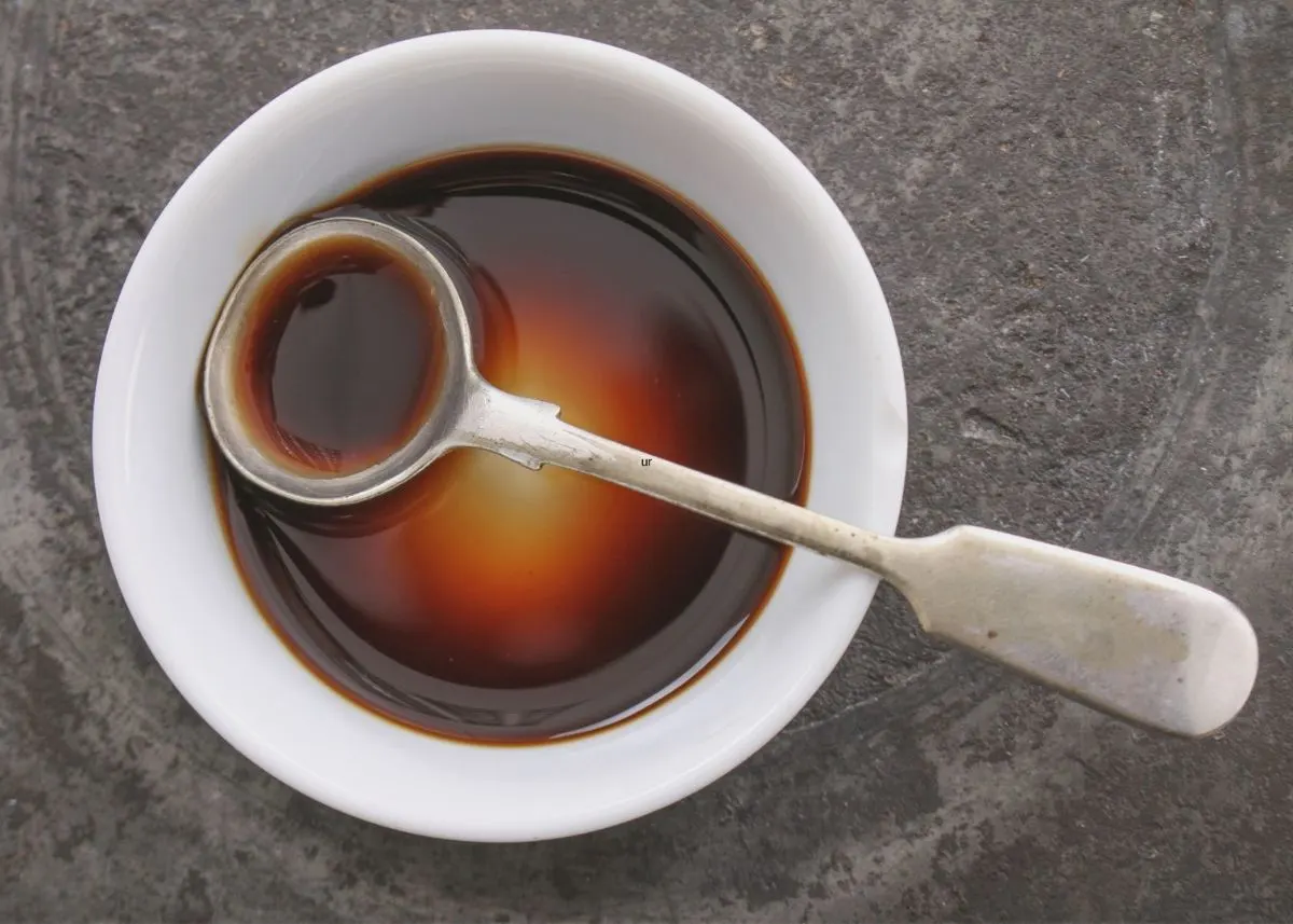 Worcestershire sauce in small white bowl with spoon large metal spoon.