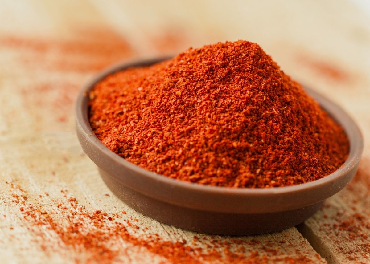 Heaping pile of bright, reddish-orange cayenne pepper in a glass serving dish.