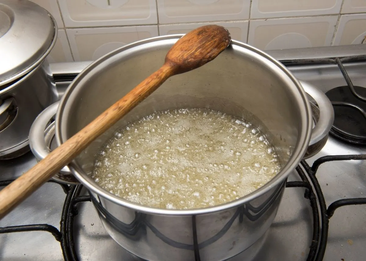 Homemade honey syrup boiling in a large stock pot over the stove.
