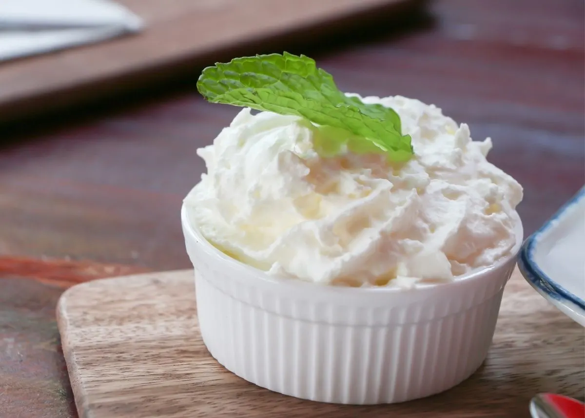 Large white ramekin filled with a mound of whipped heavy cream and mint garnish.