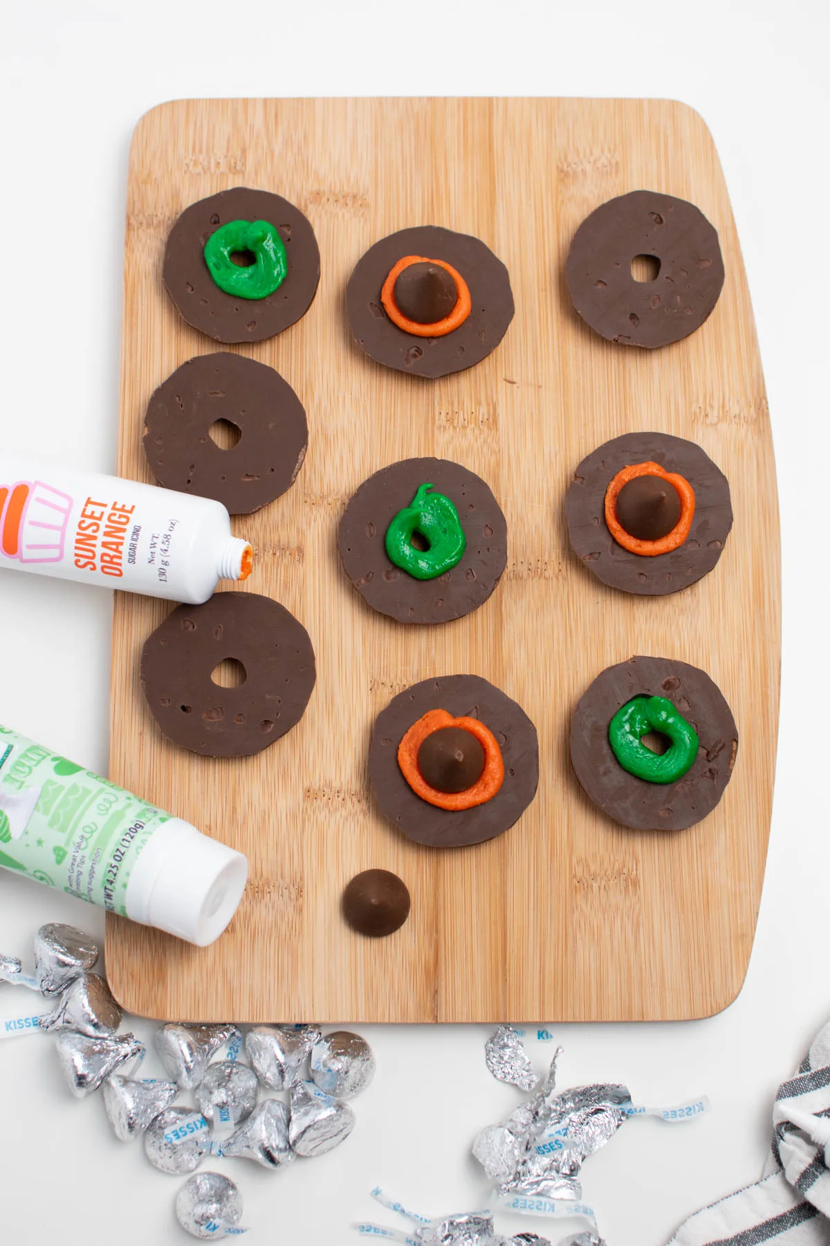 Various circles of orange and green colored frosting on fudge stripes cookies.