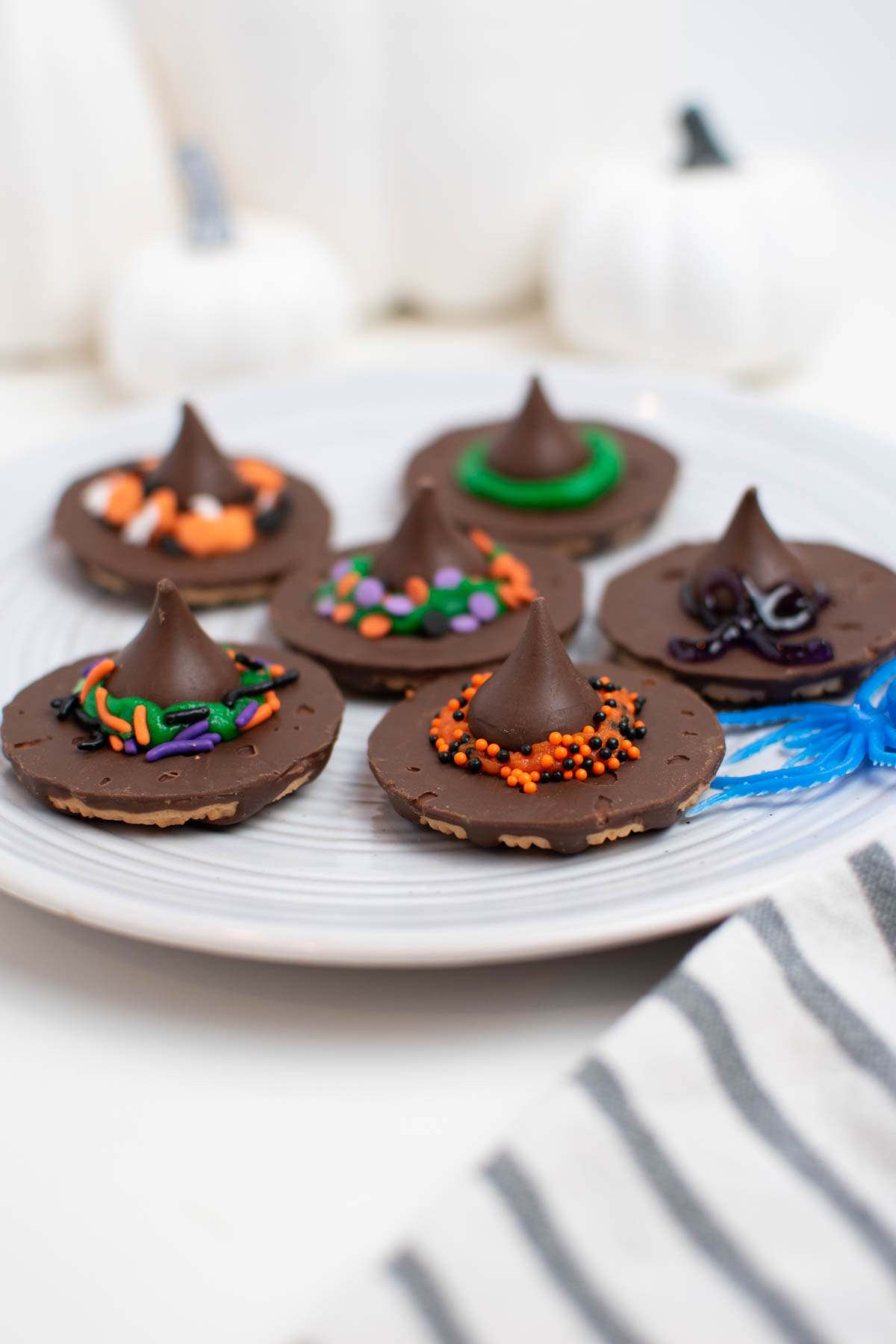Six fudge stripes witch hat cookies with sprinkle decorations on white plate.