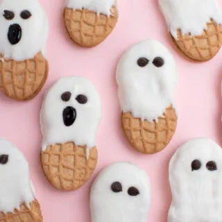 Several Nutter Butter ghosts with chocolate chip eyes on pink plate.