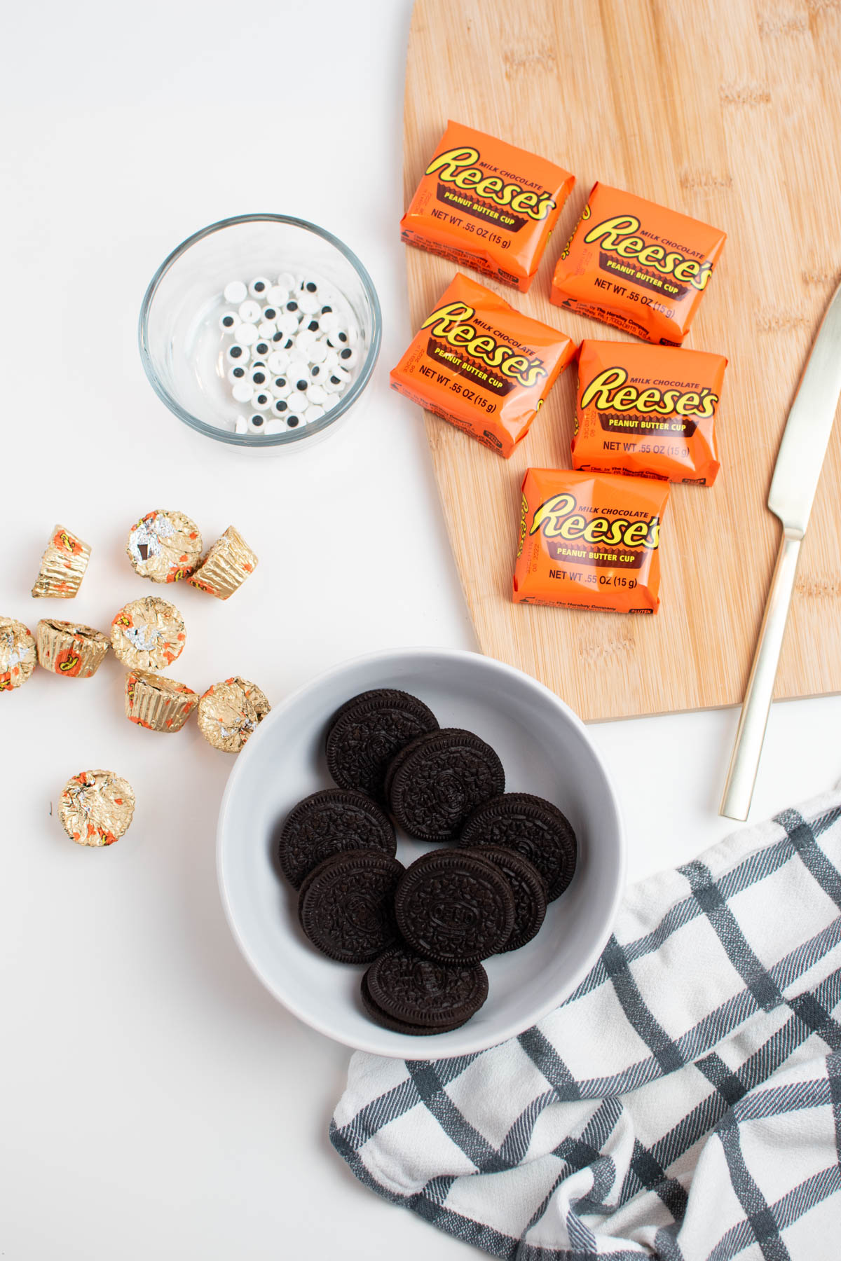 Oreo bat ingredients including Reese's cups and edible eyeballs on white table.