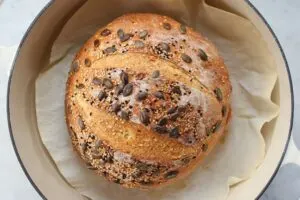 Round no knead whole bread with sesame seeds and pumpkin seeds on top.