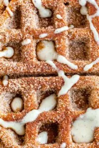 Close up of pumpkin churro waffles sprinkled with sugar and drizzled with white glaze.