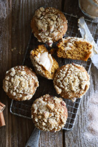 Several pumpkin pecan streusel muffins with whipped maple butter on wire cooling rack.