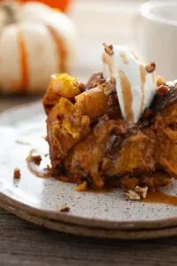 Slow cooker pumpkin bread pudding with caramel sauce and chopped nuts on top.