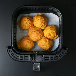 Six air fryer pumpkin biscuits in fryer basket.