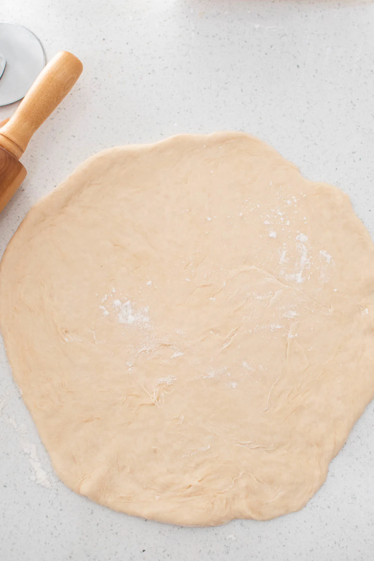 Large circle of crescent roll dough on quartz counter top.