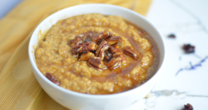 Instant pot quinoa porridge with maple syrup and pecans in white bowl.
